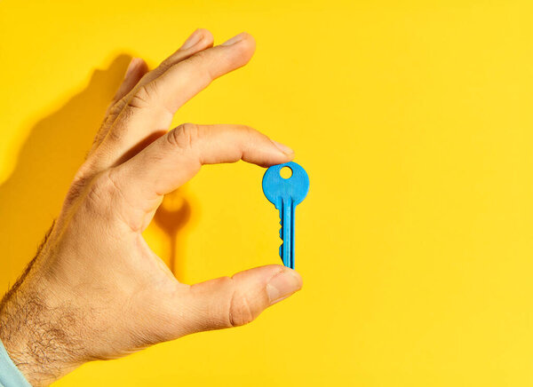 Man Hand Holding Blue Key Bright Yellow Background Copy Space Stock Picture