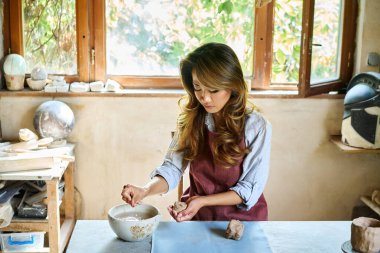 Kadın sanatçı yaratıcı atölyesinde seramik kil ile el sanatları yapıyor. Çömlekçilik seramiğinde ustalaşmak