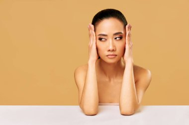 Düşünceli genç bir kadın bej arka planda izole edilmiş fotokopi odasına bakıyor ve düşünüyor. Duygular konsepti