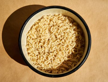 Kahverengi arka planda seramik tabakta servis edilen hazır erişteler. Basit yemek konsepti.