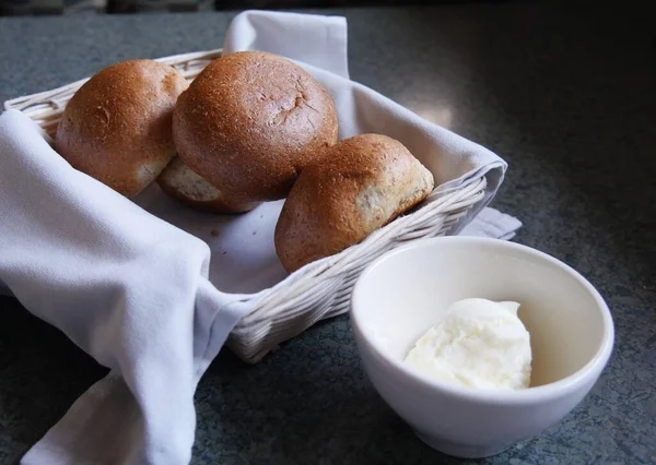 白い布にバター皿が並ぶ小さな籠に4枚のパン — ストック写真