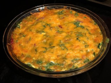 Siyah arka planda cam bir kasede ıspanaklı omlet.