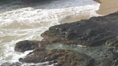 Dalgalar yavaşça Halona Sahili Koyu, Oahu, Hawaii 'nin beyaz kumlarına doğru ilerliyor.