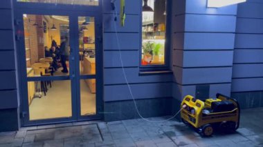 Lviv, Ukrayna - 7 Aralık 2022: Rusya 'nın Ukrayna enerji altyapısına düzenlediği büyük hava saldırıları sonrasında, şehir planlanan elektrik kesintilerinden geçerken, kafenin dışında bir elektrik jeneratörü çalışıyor