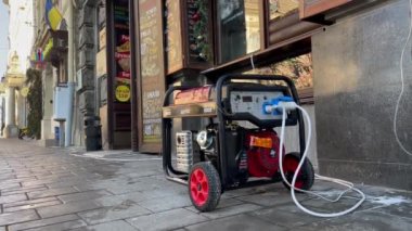 Lviv, Ukrayna - DEC 19, 2022: Rusya 'nın Ukrayna enerji altyapısına yaptığı büyük hava saldırıları sonrasında şehir planlanan elektrik kesintilerinden geçtiği için, kafenin dışında elektrik jeneratörü çalışıyor.