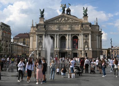 Lviv, Ukrayna - 17 Eylül 2023: Lviv kentindeki Opera ve Bale Tiyatrosu önündeki çeşmenin yakınındaki insanlar.