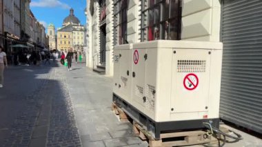 Lviv, Ukrayna - 25 Haziran 2024: Şehir Ukrayna 'da planlanan elektrik kesintilerinden geçerken, Lviv' deki kafenin dışında bir elektrik jeneratörü çalışıyor.