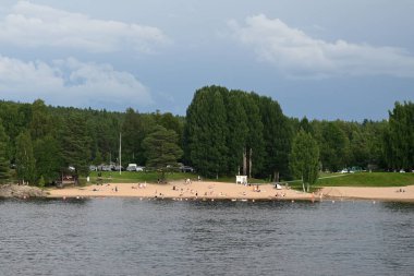 Rovaniemi, Finlandiya - 27 Temmuz 2024: Finlandiya 'nın kuzeyindeki Rovaniemi kentinde Kemijoki nehrinin kenarındaki insanlar.
