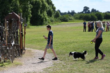 Siauliai, Lithuania - July 22, 2024: A people visiting the Hill of Crosses (Kryziu kalnas). Hill of Crosses is a major site of Catholic pilgrimage in Lithuania. clipart