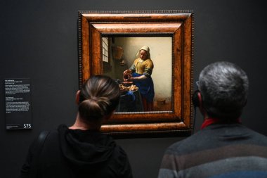 Amsterdam, Hollanda - 26 Ağustos 2024: Hollanda, Amsterdam 'daki Rijksmuseum' da Johannes Vermeer 'in Sütçü Kız yakınlarındaki ziyaretçileri.