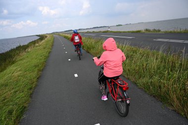 Marken, Hollanda - 25 Ağustos 2024: İnsanlar Marken köyü yakınlarında bisikletle geziyorlar.