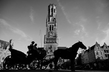 Bruges, Belçika - 28 Ağustos 2024: Eski Bruges kasabasındaki Market Meydanı 'nda (Grote Markt) Belfort (çan kulesi) yakınlarında atlı turist vagonu).