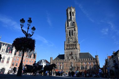 Bruges, Belçika - 28 Ağustos 2024: Eski Bruges kasabasındaki Market Meydanı 'nda (Grote Markt) Belfort (çan kulesi) yakınlarında atlı turist vagonu).