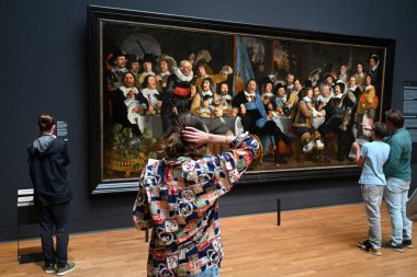 Amsterdam, Hollanda - 26 Ağustos 2024: Rijksmuseum 'da Bartholomeus van der Helst' in 1648 tarihli Munster Barışı Kutlamasında Amsterdam Sivil Muhafızları Şöleni yakınlarındaki ziyaretçiler.