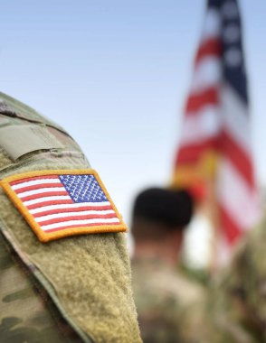 Amerikan askerleri. Amerikan ordusu. Amerikan askeri üniformasında ABD bayrağı var. Askerler tören alanının arkasında. Gaziler Günü. Anma Günü.