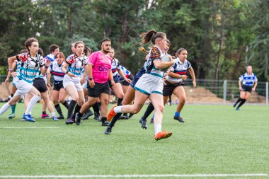 Madrid, İspanya, 13-10-2023.Evening Scrum: Genç Kolej Kadınları Alacakaranlığın büyüleyici parıltısında, üniversiteli rugby takımları dinamik düellolara katılıyor. Batan güneş, şiddetli çarpışmalara ve atletizm gösterilerine dram katıyor..