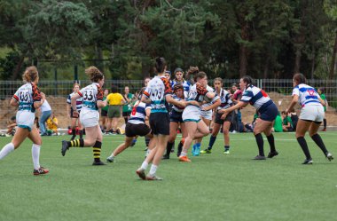 Madrid, Espaa, 13-10-2023. Rugby Rekabet: Üniversite Kadınlar Yoğun Karşılaşması. Alacakaranlığın büyüleyici parıltısıyla üniversitenin ragbi takımları dinamik düellolara girişiyor. Batan güneş, şiddetli çarpışmalara ve atletizm gösterilerine dram katıyor..