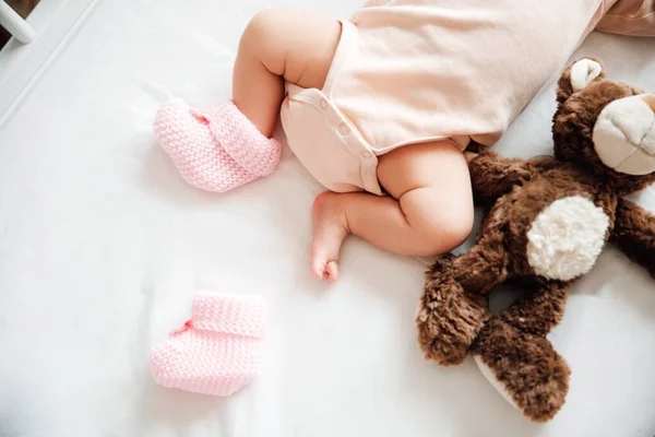 stock image Newborn baby girl in knitted shoes with a bow in a ot on a white blanket. Baby lost shoes. Childhood concept.