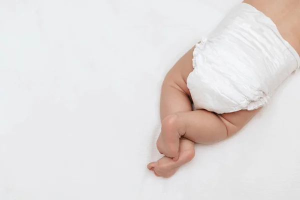 Yeni doğmuş bebek bacakları beyaz bir bezle yatağın üzerinde. Üst Manzara. Bebek bakımı ve bebek bezi değiştirme.