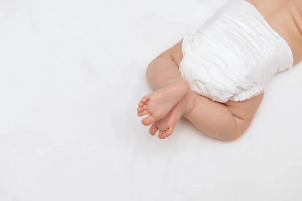 Yeni doğmuş bebek bacakları beyaz bir bezle yatağın üzerinde. Üst Manzara. Bebek bakımı ve bebek bezi değiştirme.