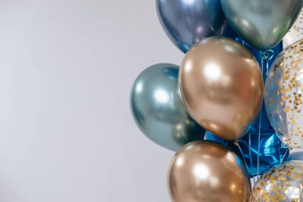 Blue and golden balloons on white background on the right. Copy space.