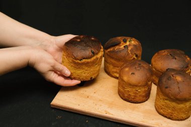 Yeni pişmiş Paskalya pastası. Kadın eli ve siyah bir arka plan. Süssüz paskalya pastaları siyah arka planda tahta bir tahtada. Paskalya pastaları soğur..