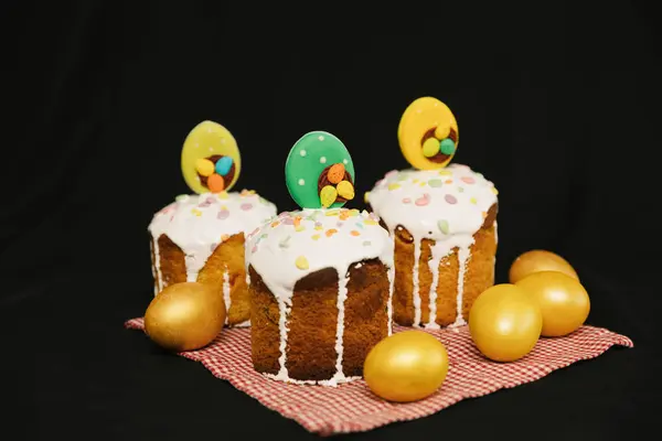 白いアイシングとカラフルな装飾と黒の背景に黄色の卵とイースターケーキ — ストック写真