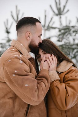 Birbirine aşık çiftler kışın sarılırlar. Adam sevgilisinin yanağını okşuyor. Kapat..