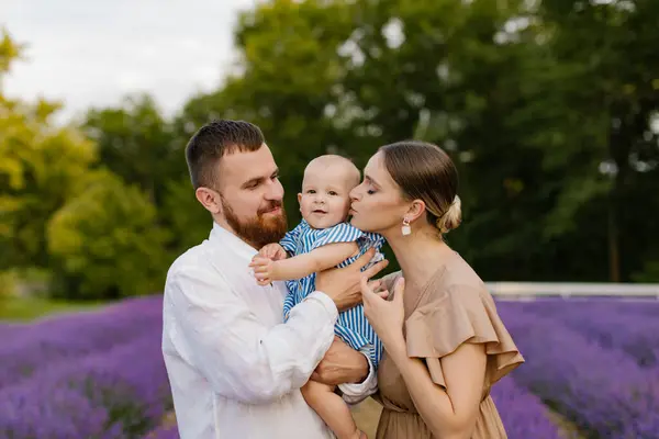 Lavanta tarlasında bebekli bir aile. Kahverengi elbiseli bir kadın ve sakallı beyaz etekli bir adam lavanta tarlasında mavi elbiseli yeni doğmuş bir kızı tutuyorlar. Aile, yaşam tarzı konsepti.