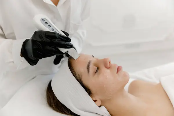 stock image Teenager girl getting ultrasonic facial skin cleansing treatment by dermatologist. Ultrasonic facial cleansing on teen's face. Teen skin.