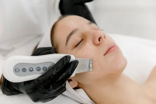 stock image Teenager girl getting ultrasonic facial skin cleansing treatment by dermatologist. Ultrasonic facial cleansing on teen's face. Teen skin.