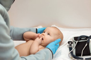 Doktor bebeğin sağlığını kontrol ediyor. Doktor bebeğin kafasına dokunuyor..