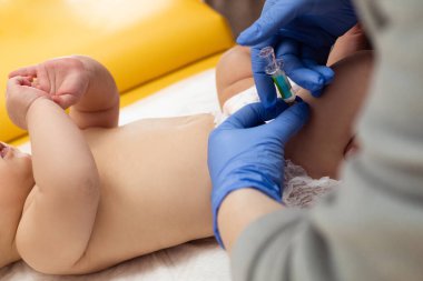 Küçük bebeğe aşı uygulayan bir çocuk doktoru. Pediyatrist küçük bebeğe bacağından iğne yapıyor. Kapatın. Çocuk sağlığı ve hastalık önleme.