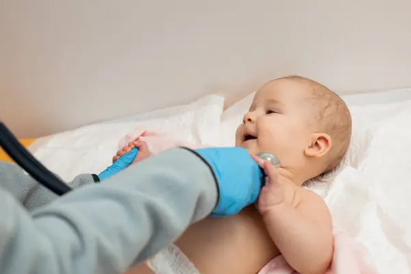 Çocuk doktoru, bebeğini muayene ediyor. Bir doktor bir çocuğun kalp atışlarını dinlemek için steteskop kullanır. Kapat..