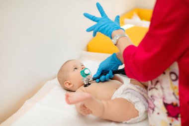 Çocuk doktoru, bebeğini muayene ediyor. Çocuğun kalp atışlarını dinlemek için steteskop kullanan bir doktor. Kapat..