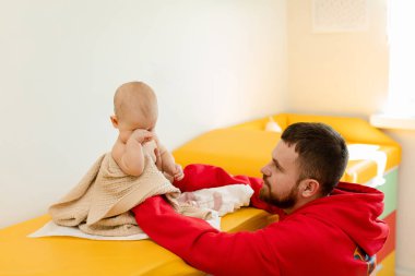 Çocuk doktoru, bebeğini muayene ediyor. Çocuğun kalp atışlarını dinlemek için steteskop kullanan bir doktor. Kapat..