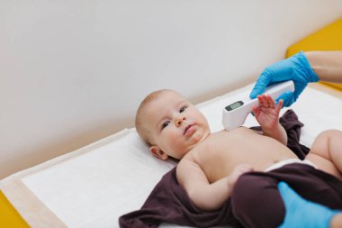 Çocuk doktoru, bebeğini muayene ediyor. Çocuğun kalp atışlarını dinlemek için steteskop kullanan bir doktor. Kapat..