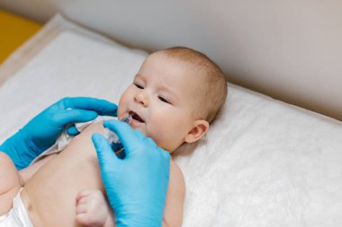 Çocuk doktoru, küçük bebeğe rotavirüs enfeksiyonuna karşı ağız aşısı yapıyor. Çocuk sağlığı ve hastalık önleme.