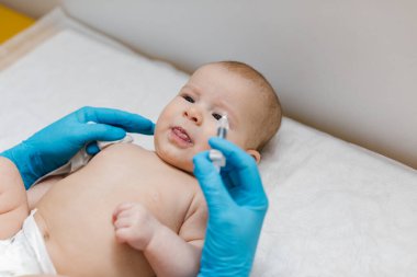 Çocuk doktoru, küçük bebeğe rotavirüs enfeksiyonuna karşı ağız aşısı yapıyor. Çocuk sağlığı ve hastalık önleme.