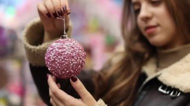 Elinde parlak pembe bir Noel balosu tutan kadın. Tatil sezonunun şenlikli ve rahat atmosferini yakalar. Kadının elindeki pembe Noel süsü. Kapat.. 