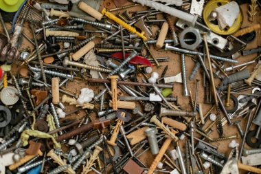 Kaotik bir yığın vida, cıvata, çivi, duvar bujileri, yıkama makineleri ve metal parçalar. Farklı şekillerde, boyutlarda ve malzemelerde eski ve yeni bağlayıcıların karışımı. Yakın çekim, atölye araçları.