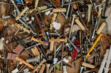 Kaotik bir yığın vida, cıvata, çivi, duvar bujileri, yıkama makineleri ve metal parçalar. Farklı şekillerde, boyutlarda ve malzemelerde eski ve yeni bağlayıcıların karışımı. Yakın çekim, atölye araçları.