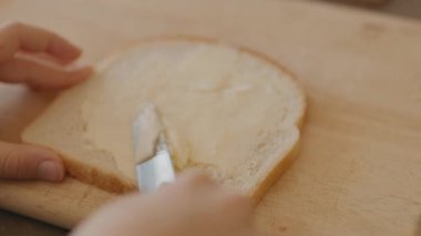 Ergenin Sandviç Yapan Elleri. Ekmek dilimine tereyağı sürülüyor.