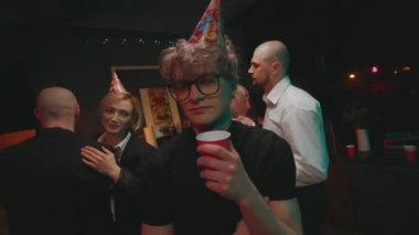 Şirket Partisi. Çiftler halinde dans eden iki erkek ve kadın. Bir tane komik kıvırcık adam ayakta duruyor ve içiyor. İşten sonra ofis çalışanları için eğlence.