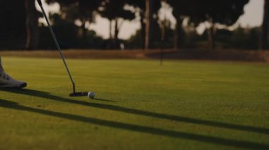 Adam topa sopayla vuruyor. Golf Yeşil Golf sahasında. Yüz görünmezdir. Kolayca Topa Tekmeleyen Adamın Bacakları.