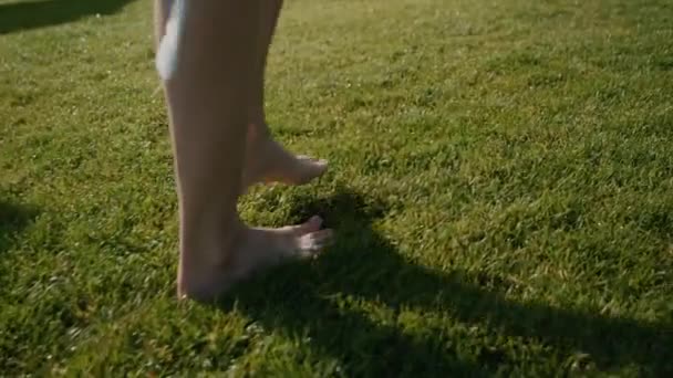 若い女の子の足 彼女は草の上にベアフットを歩いている 健康的なライフスタイルのコンセプト 美しい晴れた日 — ストック動画