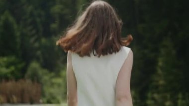 Beyaz Ceketli Büyük Küpeli Genç Esmer. Orman çevresi. Ormanın Arkaplanına Karşı Kız Dönüyor ve Poz Veriyor.