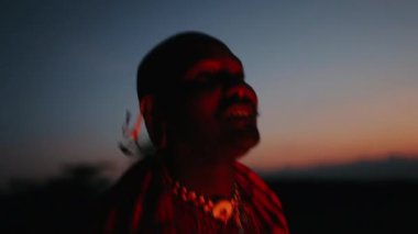 Ateşin yanında geleneksel giysiler içinde Afrika kabilesinden bir adamın yüzü. Afrika 'da Gece. Kenya.