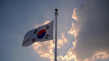 Güney Kore bayrağı gökyüzünde görkemli bir şekilde dalgalanıyor. Ülkenin ulusal gurur ve birliğini temsil ediyor.