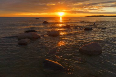 Kayalık bir sahil üzerinde kızıl gökyüzü. Gün batımı manzarası.
